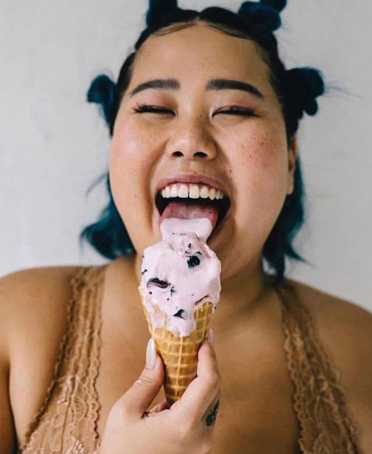 a woman eating an ice cream cone with her eyes closed and mouth wide open,