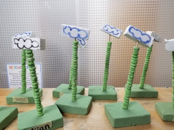 four green and white sculptures on top of a wooden table next to a sign that says cloud