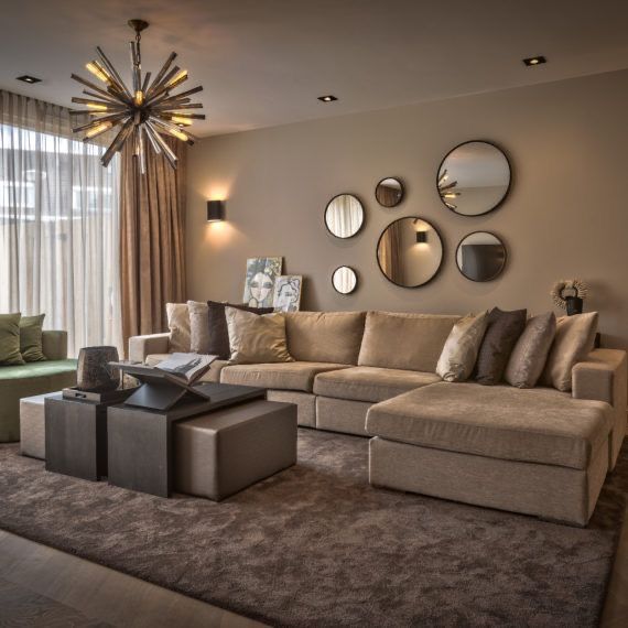 a living room filled with furniture and mirrors on the wall above it's windows