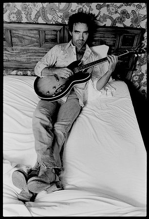 a man sitting on a bed with a guitar