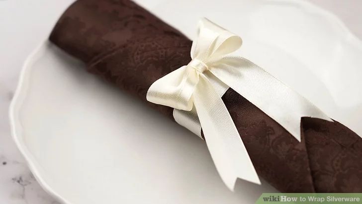 a white plate topped with a piece of chocolate cake covered in a bow and ribbon