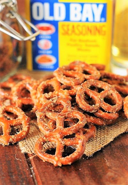 several pretzels on a wooden table next to an old bay seasoning bottle