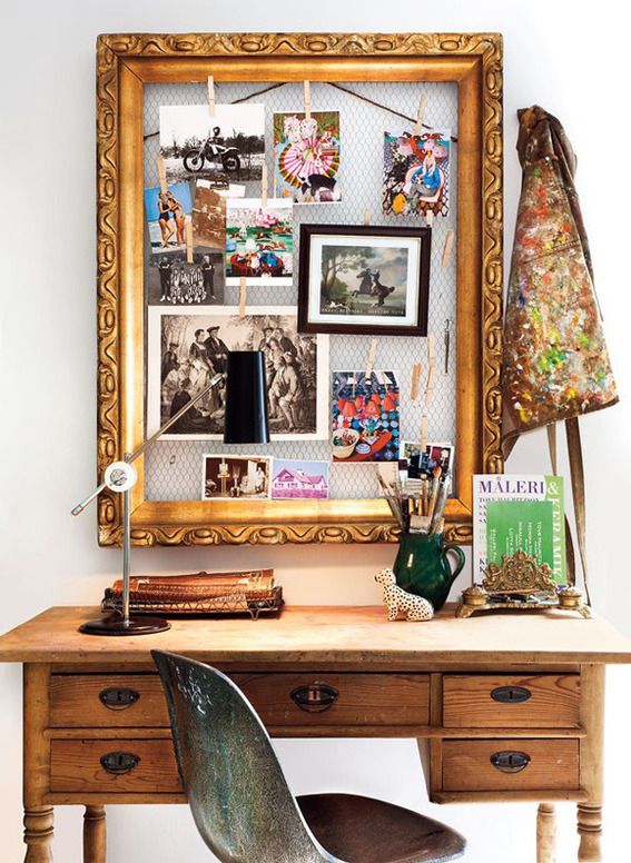 a wooden desk topped with a metal chair next to a wall mounted art work frame