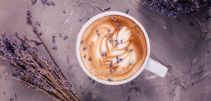 an overhead view of a cappuccino with lavender sprigs on the side