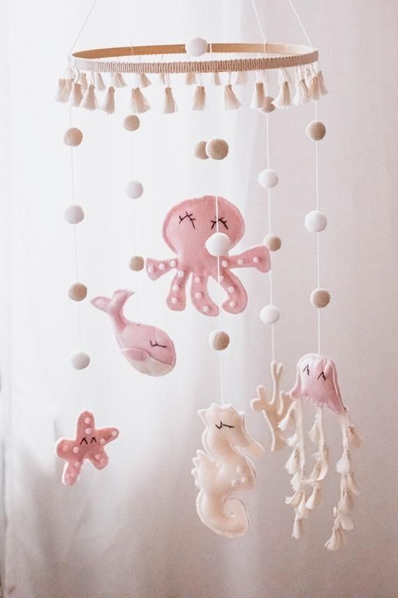 a pink and white crib mobile with sea animals