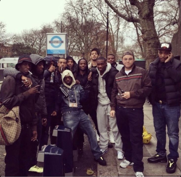 a group of young men standing next to each other on a sidewalk with suitcases