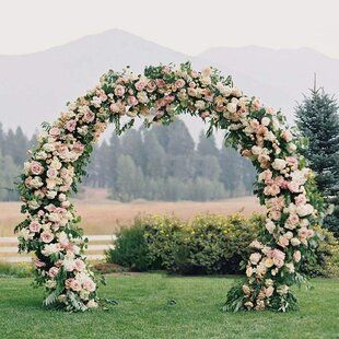 an outdoor wedding ceremony setup with flowers and greenery on the grass in front of mountains