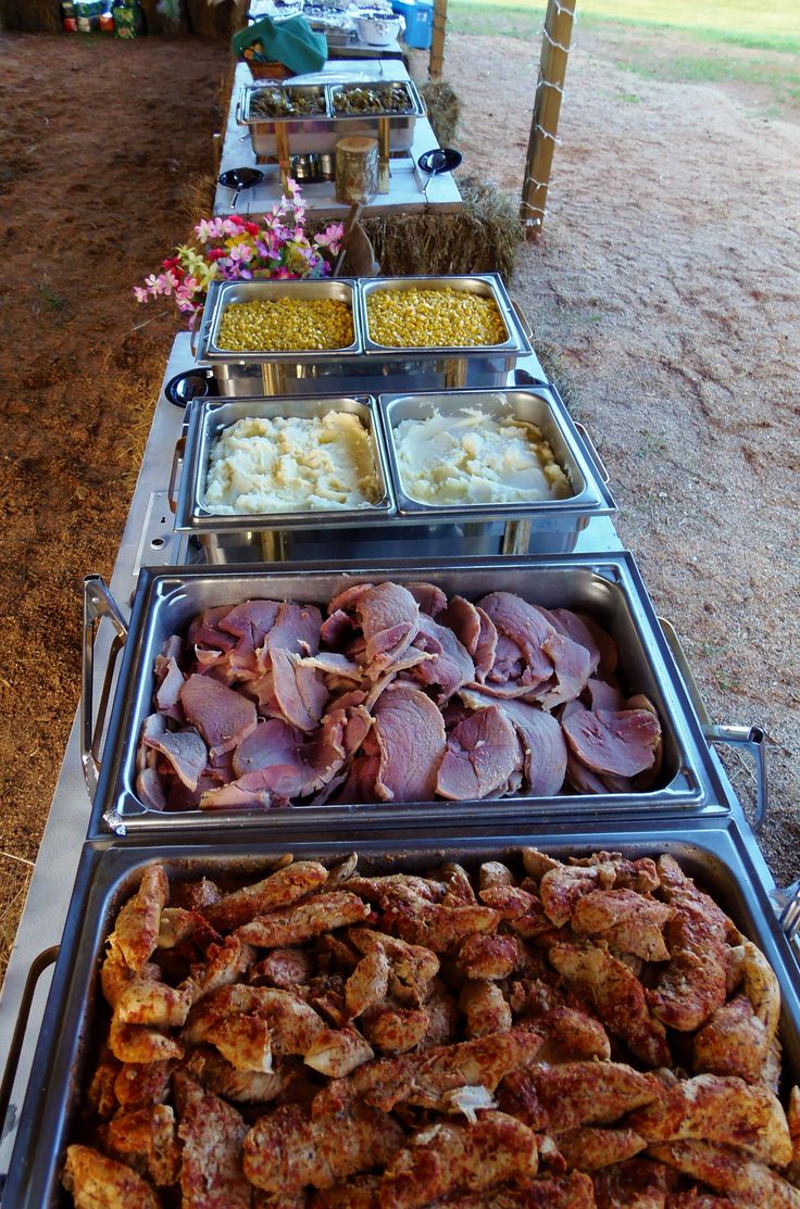 a long table filled with lots of different types of food on top of metal trays