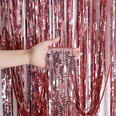 a hand is reaching out from behind some red tinseled streamers that are hanging in front of a white wall