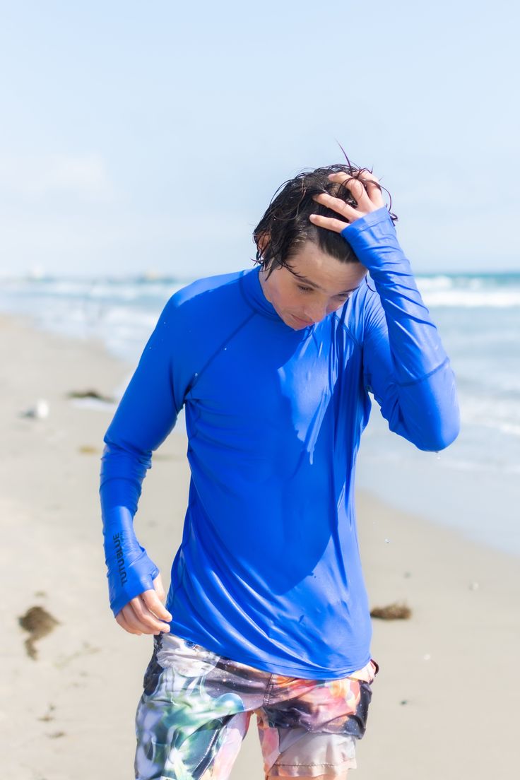 a man standing on top of a sandy beach next to the ocean holding his head