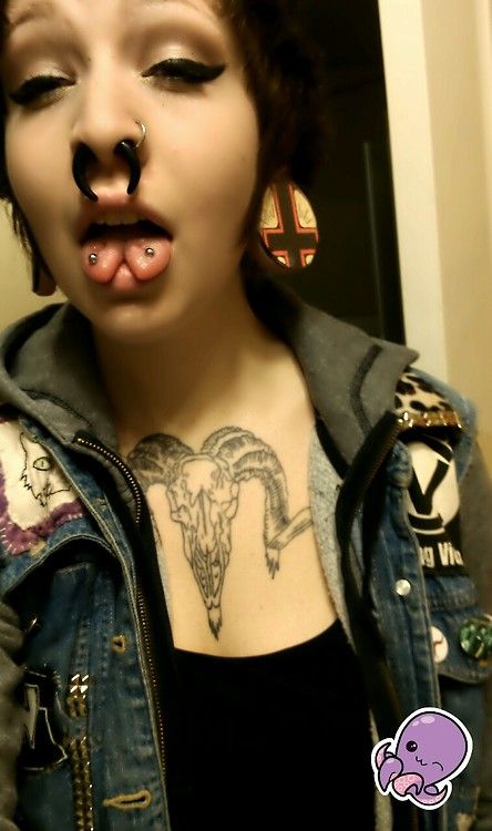 a woman with piercings sticking out her tongue