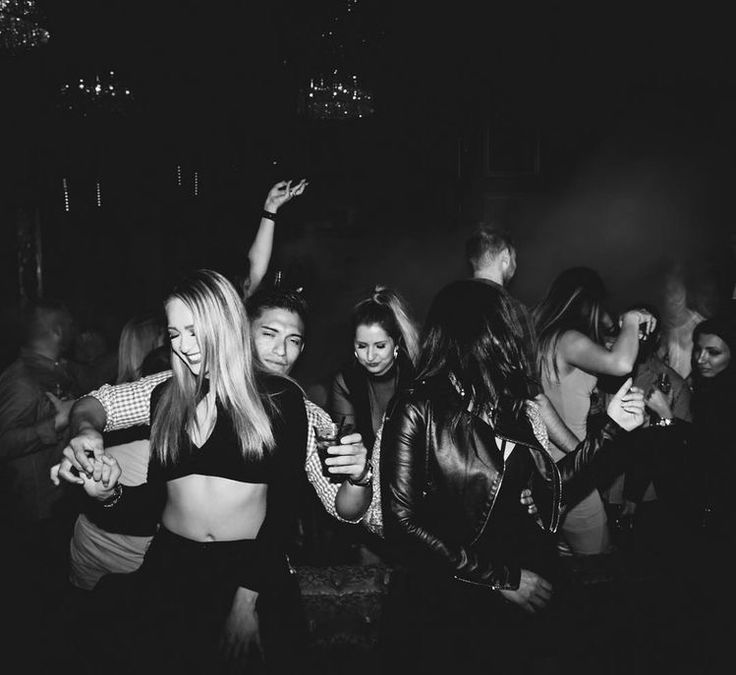 black and white photograph of people dancing in the dark with their arms around each other