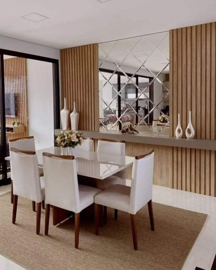 a dining room table with white chairs and a mirror on the wall in front of it