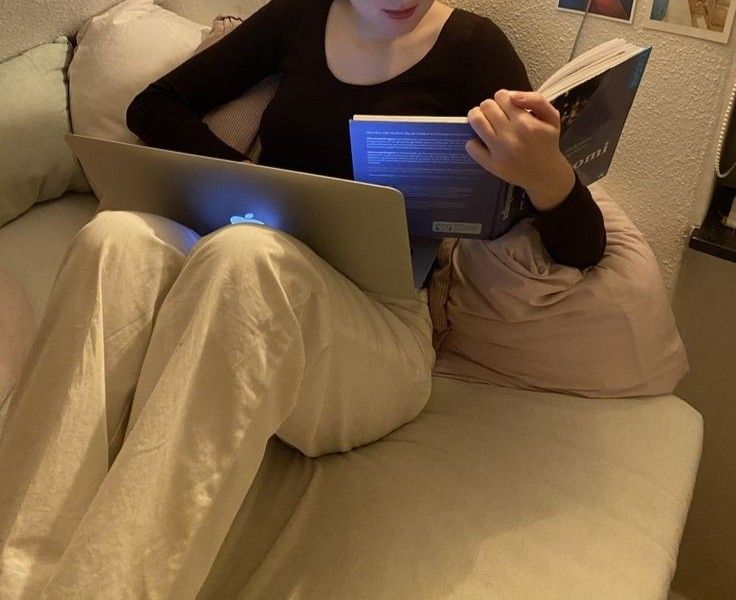 a woman sitting on a couch reading a book