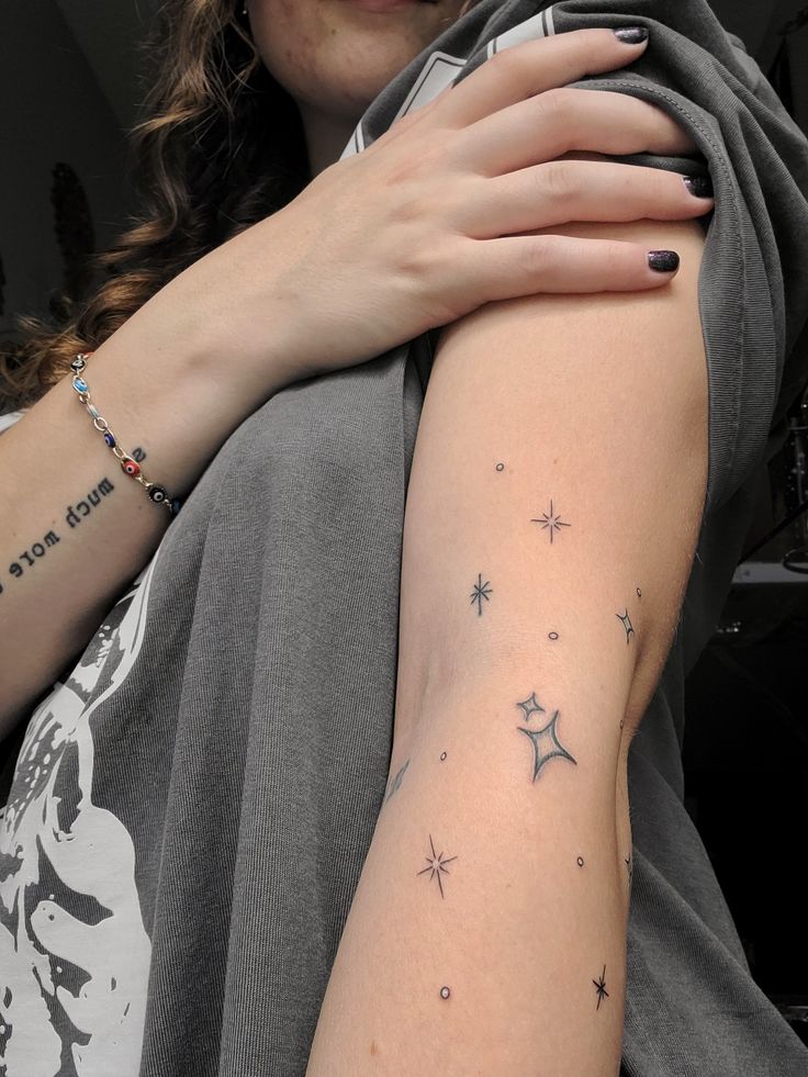 Star tattoo on arm Star Patchwork Tattoos, Stars Around Moon Tattoo, Scattered Star Tattoos, Star Arm Wrap Tattoo, Sparkle Tattoo Sleeve Filler, Thigh Star Tattoo, Star Hip Tattoos Women, Star Arm Band Tattoo, Twinkle Stars Tattoo