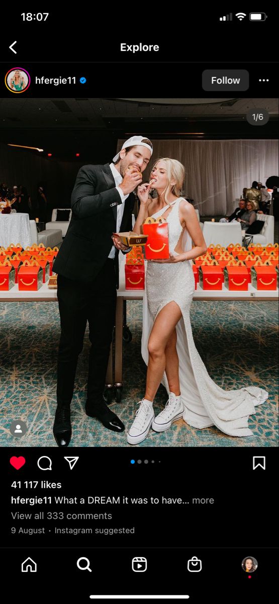 a man and woman standing next to each other in front of a table with orange cups