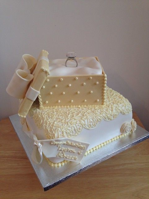 a wedding cake that has been decorated with pearls and bows on the top, sitting on a table