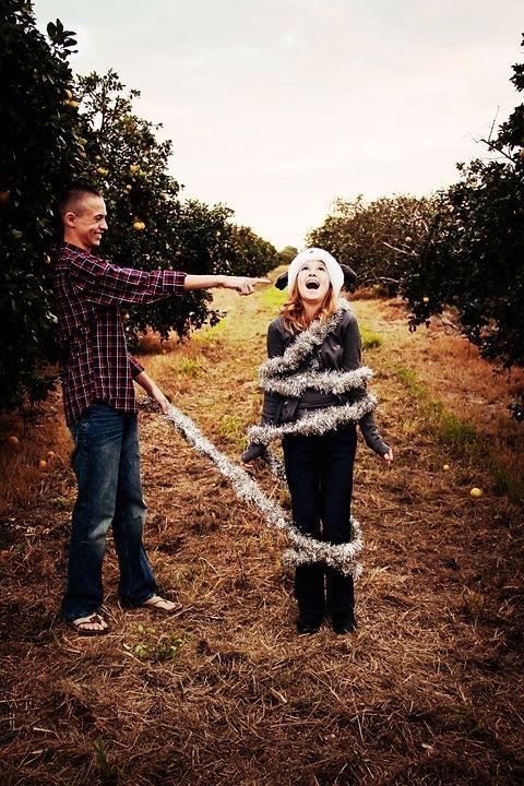 a man and woman standing in an apple orchard with their arms out to each other