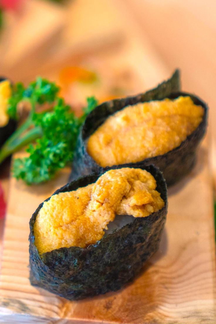 two sushi rolls on a wooden cutting board with broccoli