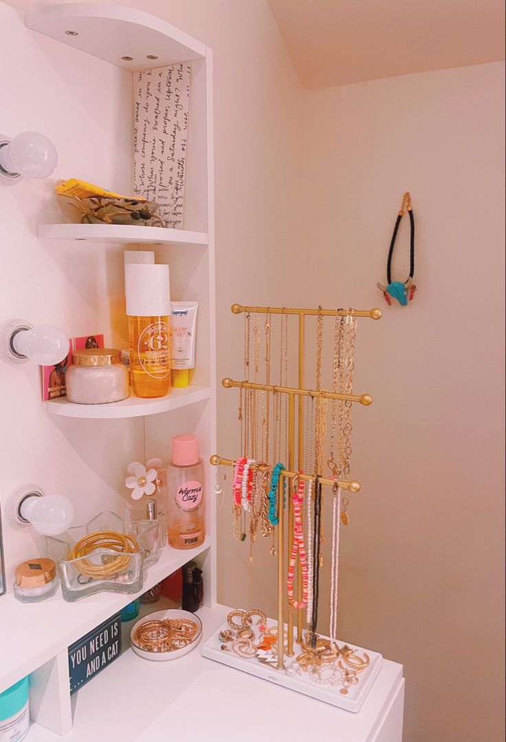 a white bathroom with gold accessories and jewelry on the shelf next to the bathtub