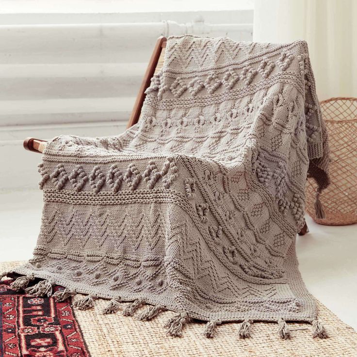 a chair with a blanket on top of it next to a rug and vases