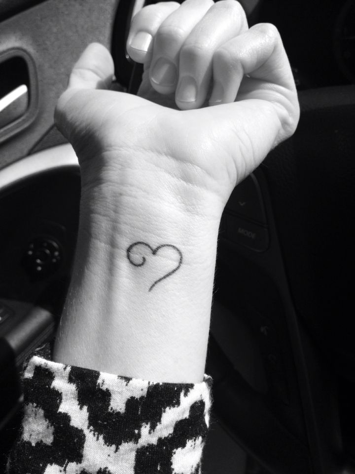 a small heart tattoo on the wrist