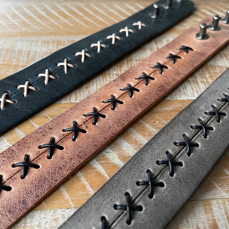 three different colored leather bracelets with crosses on them