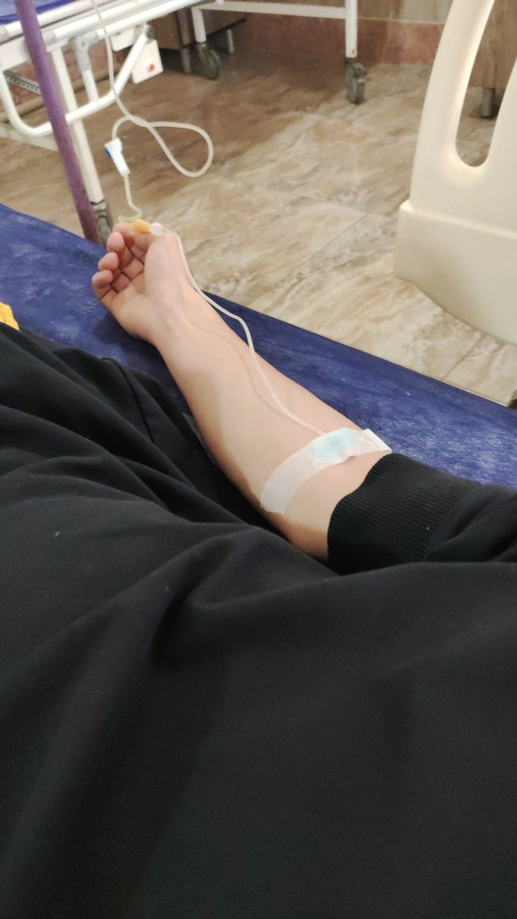 a person laying in a hospital bed with an iv attached to their arm and hand