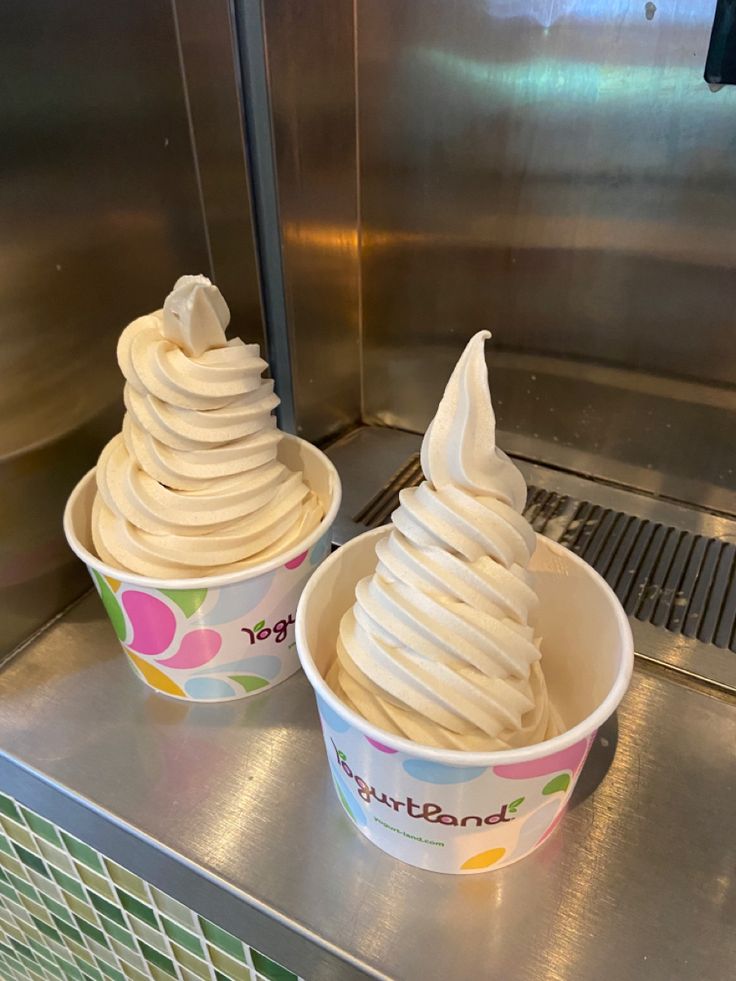 two ice cream cones sitting on top of a metal counter next to eachother