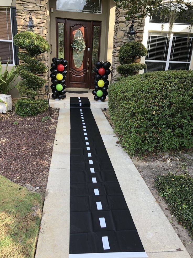 a black and white striped road leading to a house with balloons on the front door