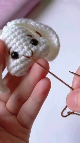 someone is holding a tiny crocheted teddy bear in their left hand while knitting it