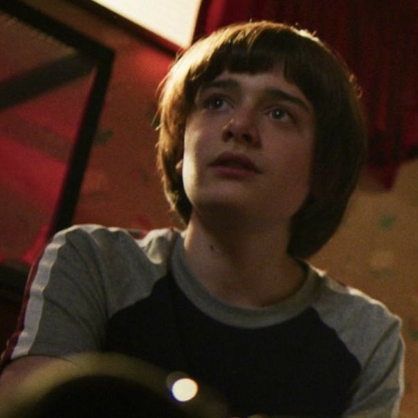 a young boy sitting in front of a red light with his hands folded out to the side