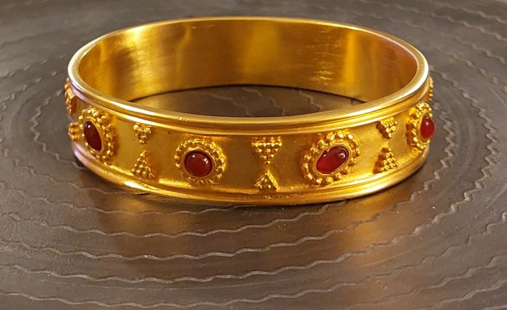 1st Century BC to 2nd Century AD reproduction bangle.  I believe this is based on a Parthian neck ring called the Star Cresent. This is beautiful and thickly gold plated. It has granulation and is set with 9 cabochon carnelians.  It was made in 1993.  It is gold over pewter.  Dimensions: 3 x 2-1/2 inches x 17.5 mm wide. Recommend for a wrist 7 inches or under. It is not adjustable. Photographed with and without flash to show how rich the finish is. Ceremonial Polished Gold Bangle, Ceremonial Gold Bangle With Polished Finish, Gold Bangle With Polished Finish For Ceremonial Events, Gold Bangle With Decorative Band As Gift, Ceremonial Byzantine Bangle Jewelry, Traditional Gold Jewelry With Decorative Band, Traditional Gold Bangle With Polished Finish, Neck Ring, Air Force Base