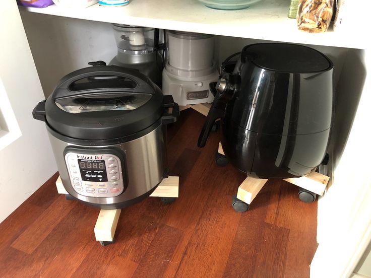 two crockpots are sitting on the floor next to each other in front of a shelf