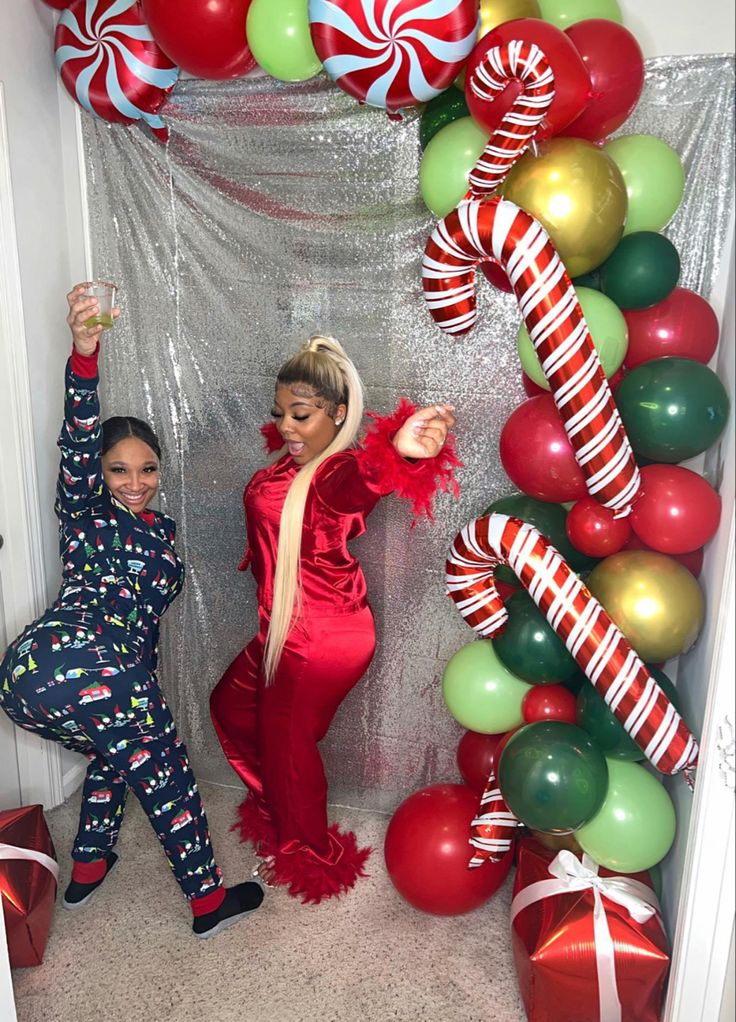 two women dressed in red and green are posing for the camera with candy canes