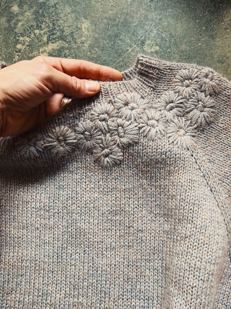 someone is stitching up the details on a sweater