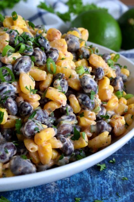 a white bowl filled with macaroni salad and garnished with parsley