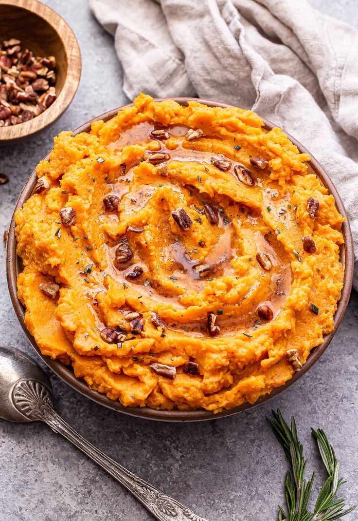 a bowl filled with mashed sweet potatoes topped with pecans