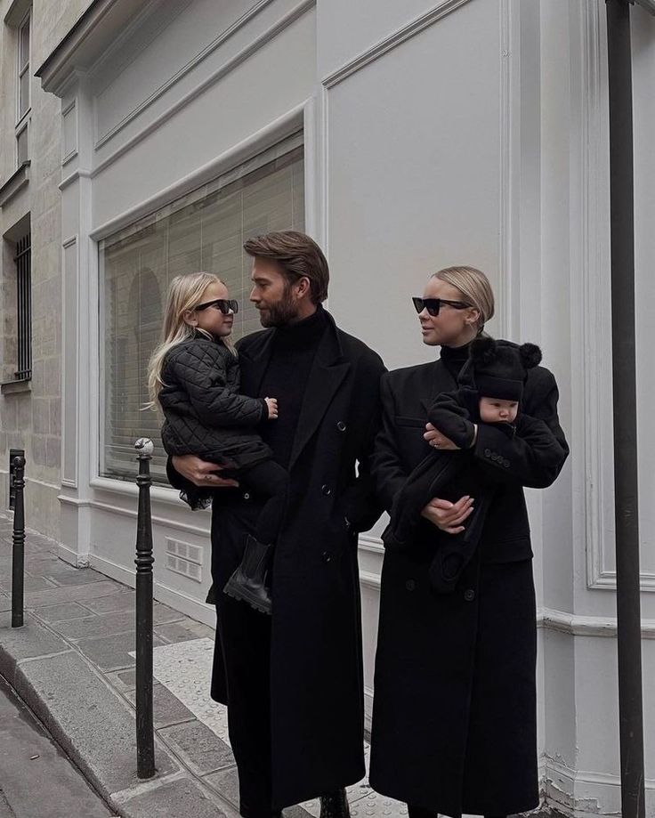 a man and two women are walking down the street while holding their baby daughter in her arms