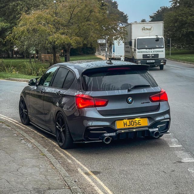 a grey bmw car driving down the road next to a white truck and some trees