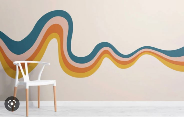 a white chair sitting in front of a wall with an abstract design painted on it