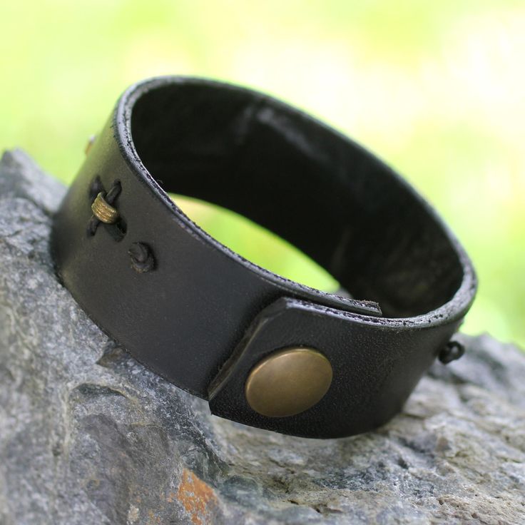 Men's ruggedly handsome black leather bracelet by Gill Quarcoopome. The masculine bracelet is adorned with a clever arrangement of crimped antique brass inserts which have been hand-stitched with leather cords creating a discreet contrast of powerful elegance. Leather Brass Inserts Snap clasp Avoid contact with water Handmade in & fairly traded from Ghana