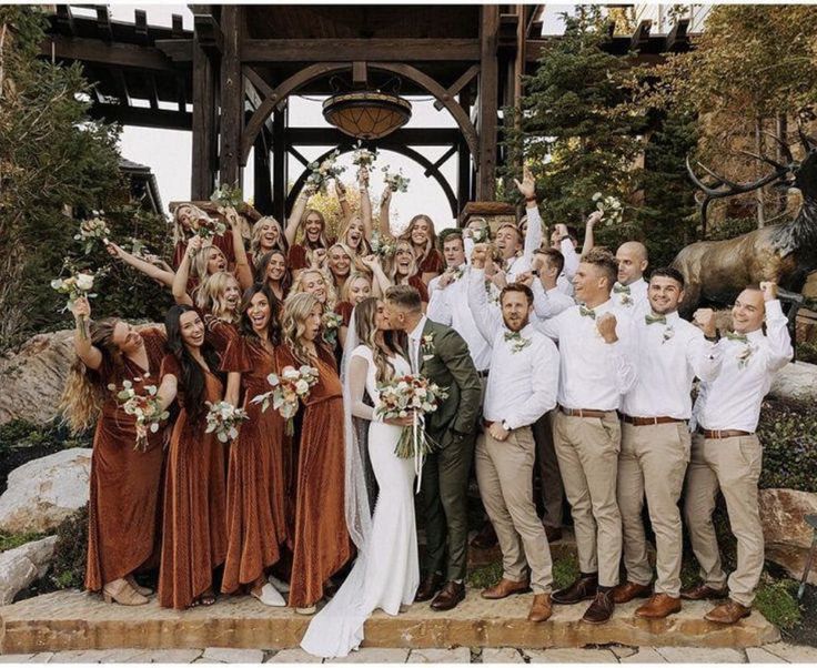 a group of people standing next to each other in front of a wooden structure with flowers