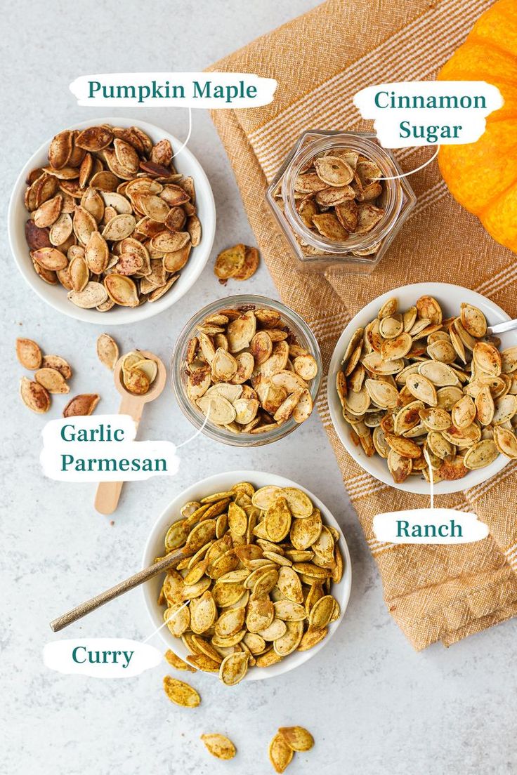 four bowls filled with nuts on top of a table next to pumpkins and other ingredients