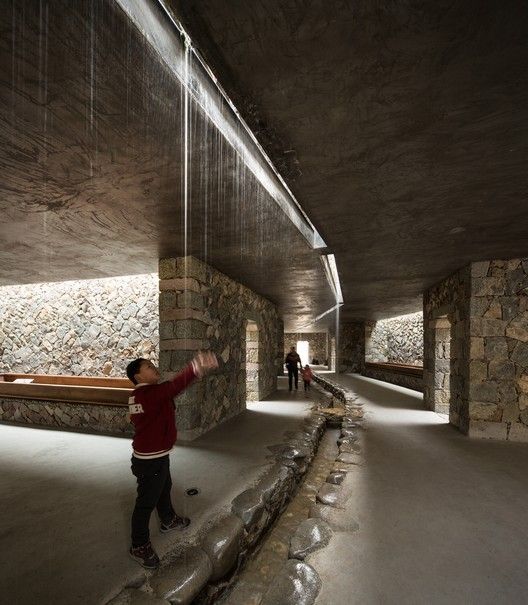 a man is standing in the middle of a room with stone walls and water flowing from it