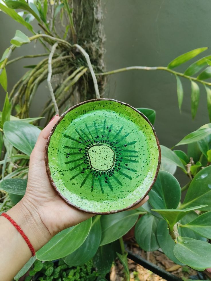 a person holding up a green bowl with an intricate design on the outside and inside