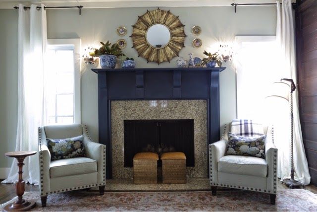 a living room filled with furniture and a fire place under a mirror on the wall