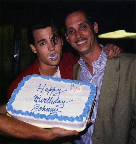 two men pose with a birthday cake in front of them