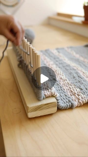 a person is knitting on a wooden table