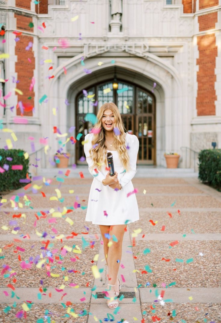 a woman standing in front of a building surrounded by confetti